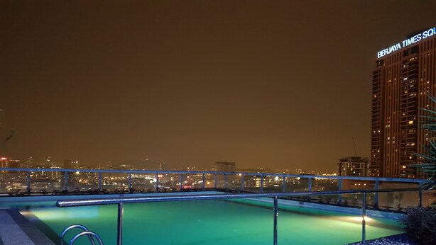 Ein Pool auf dem Dach mit Blick auf die nächtliche Stadtlandschaft.