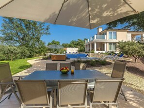 An outdoor patio with a table and chairs, a hot tub, and a swimming pool.