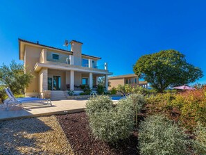 A modern two-story house with a large patio and a swimming pool.
