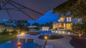 Ein Außenbereich mit Terrasse, Pool, Liegestühlen und einem Esstisch.