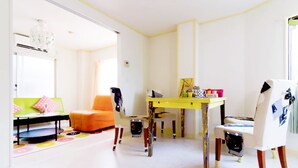 A bright, modern room with a yellow table, orange and white chairs, and a green sofa. - N ° 5  CONDOMINIUM: First floor Corner Apartment ;  Safe Residential Area. (Osaka)