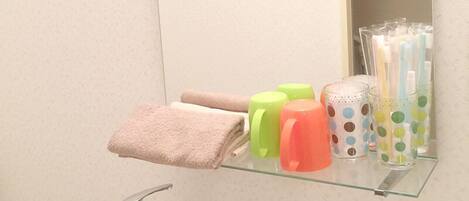 A bathroom with a white sink, a mirror, and a shelf with toiletries.