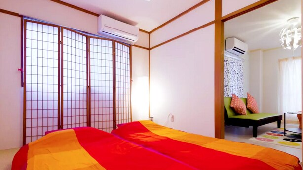 A room with a bed, a futon, and a sliding door. - N ° 5  CONDOMINIUM: First floor Corner Apartment ;  Safe Residential Area. (Osaka)