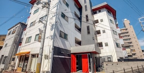 A multi-story building with a red entrance, a visible sign reading "ASTERIA N°5", and a bike parked outside.