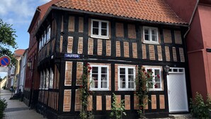 A traditional half-timbered building with a red-tiled roof, a visible antenna, and a street sign indicating 'Ladegårdsgade'. - Cozy town house in the center of Assens, close to the harbor. (Assens)