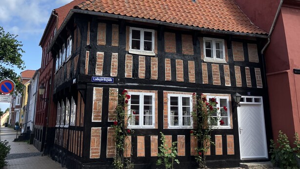 A traditional half-timbered building with a red-tiled roof, a visible antenna, and a street sign indicating 'Ladegårdsgade'. - Cozy town house in the center of Assens, close to the harbor. (Assens)