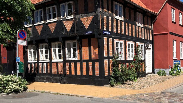 A traditional half-timbered building with a red-tiled roof, a sign indicating parking restrictions, and a clear blue sky. - Cozy town house in the center of Assens, close to the harbor. (Assens)
