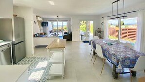 A spacious living area with a kitchen, dining table, and a view of the outdoors. - Villenpark Playa Arena House Ocean (Lloret de Mar)
