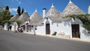 A row of traditional stone-roofed houses with white walls and a clear blue sky. - Villa with large private pool, stunning views, fantastic for cycling/ walking (Martina Franca)