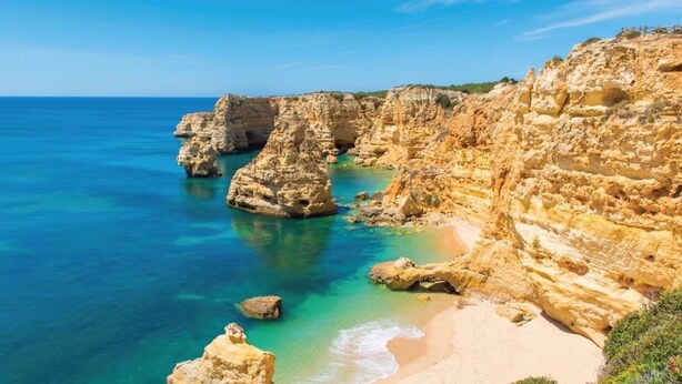 A coastal landscape with rocky cliffs and clear blue waters.