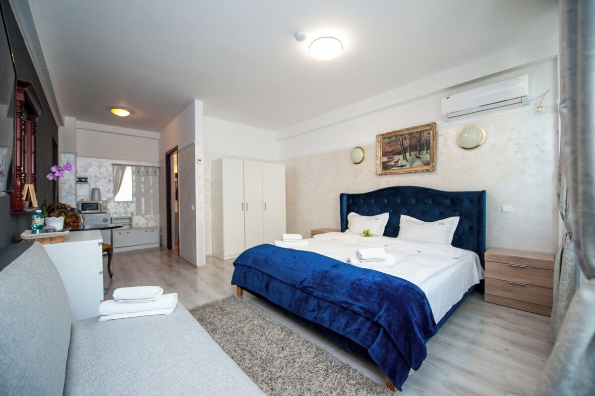 A bedroom with a bed, a desk, a wardrobe, and an air conditioning unit.