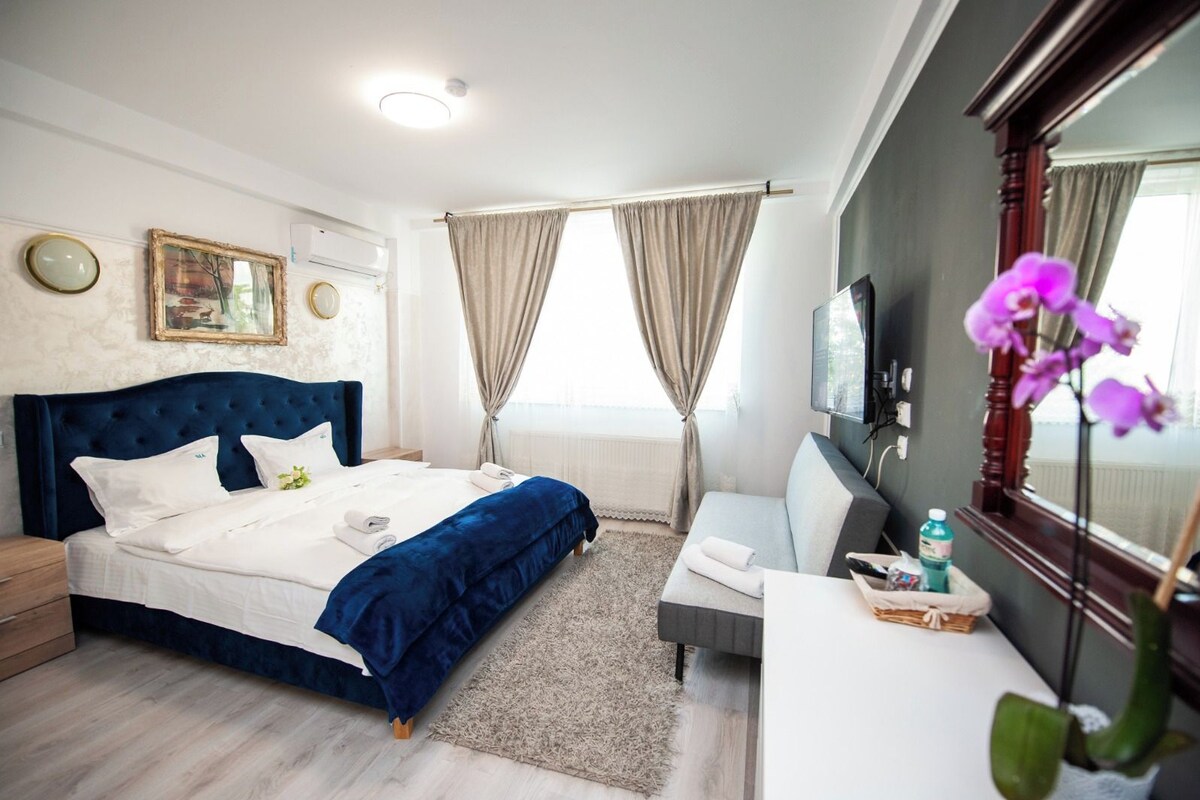 A hotel room with a bed, a desk, a TV, and a window with curtains.