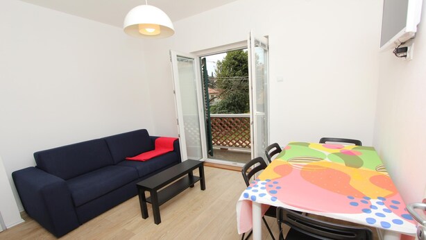 A compact living space with a sofa, a small table, and a colorful tablecloth-covered table. - PARIS One-Bedroom Apartment (Rovinj)