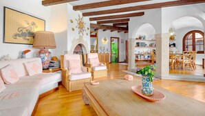 Amplia sala de estar con techos altos y vigas a la vista, que incluye un sofá, sillones, una mesa de centro y una estantería.