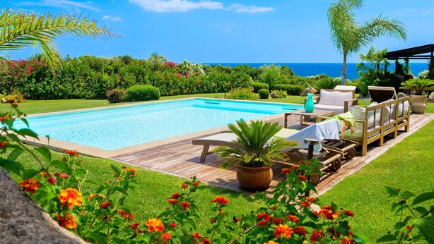 Zona junto a la piscina con muelle de madera, sillas de descanso y vistas al océano.