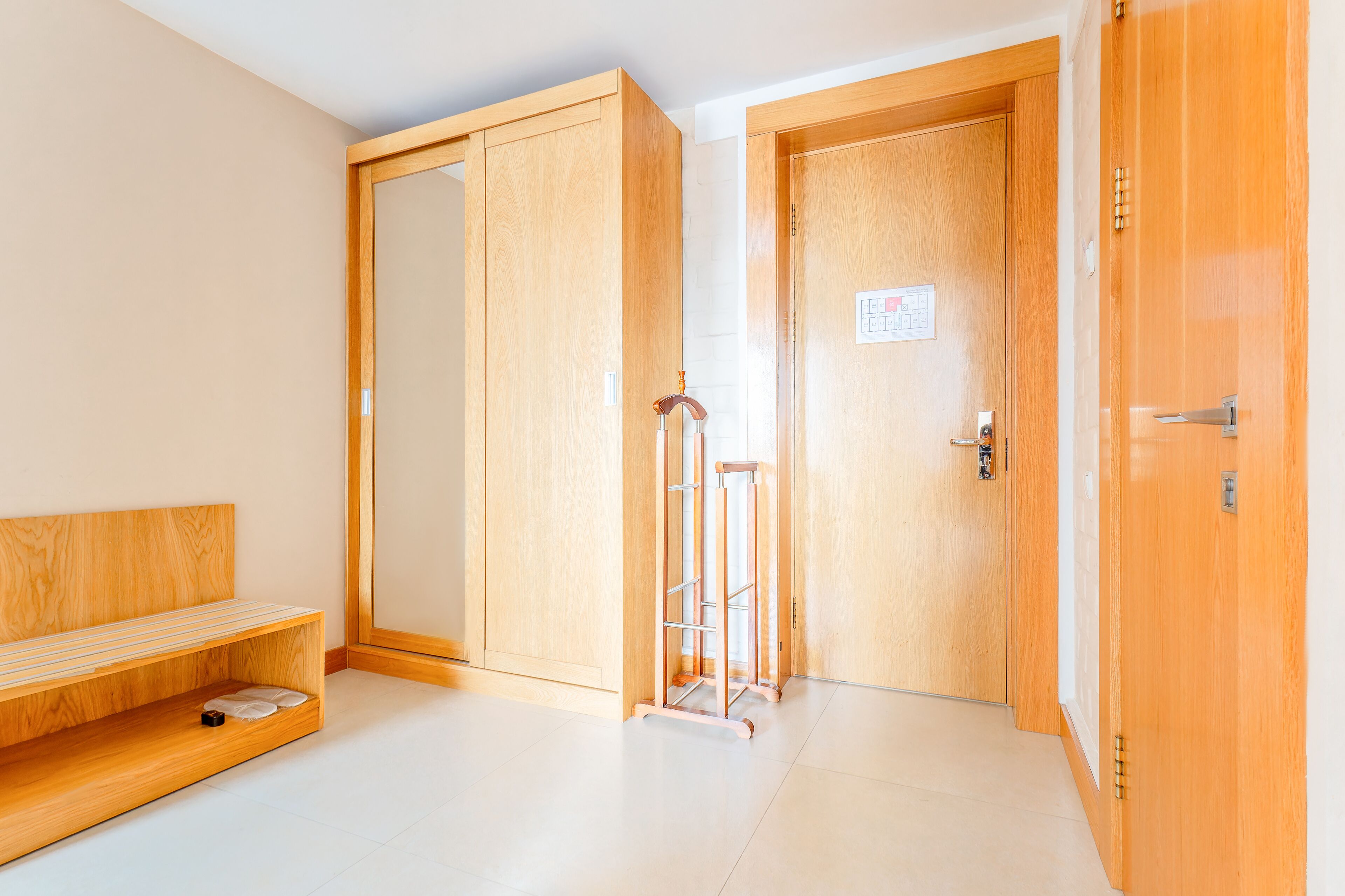 Ein Zimmer mit einer hölzernen Bank, einem Schrank und einer Tür mit einem Schild.