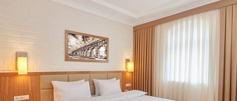 A neatly made bed with a headboard, a bedside table with a lamp, and a framed picture on the wall.