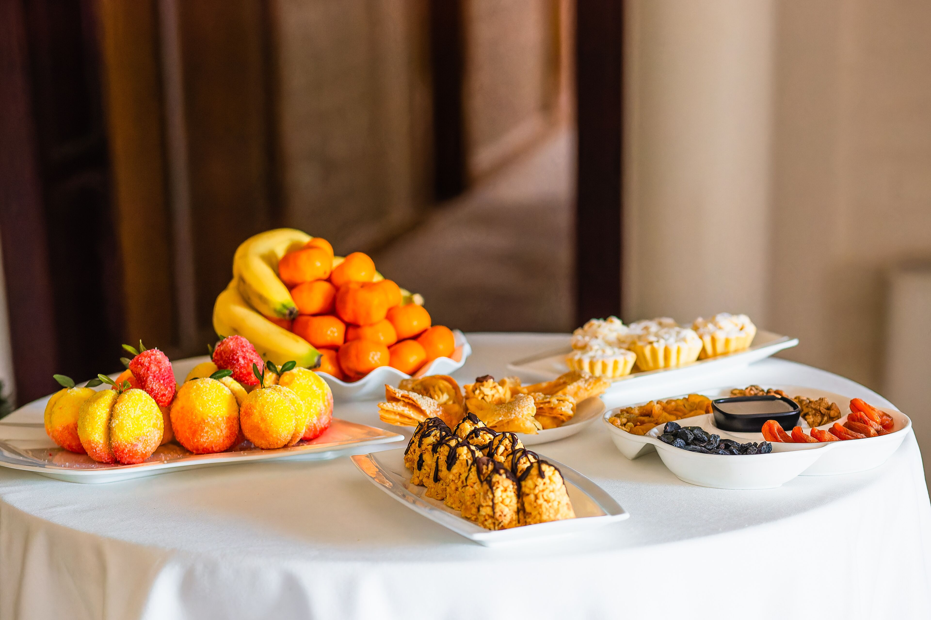 Una taula de buffet amb diferents plats, incloent fruita, pastissos i postres.