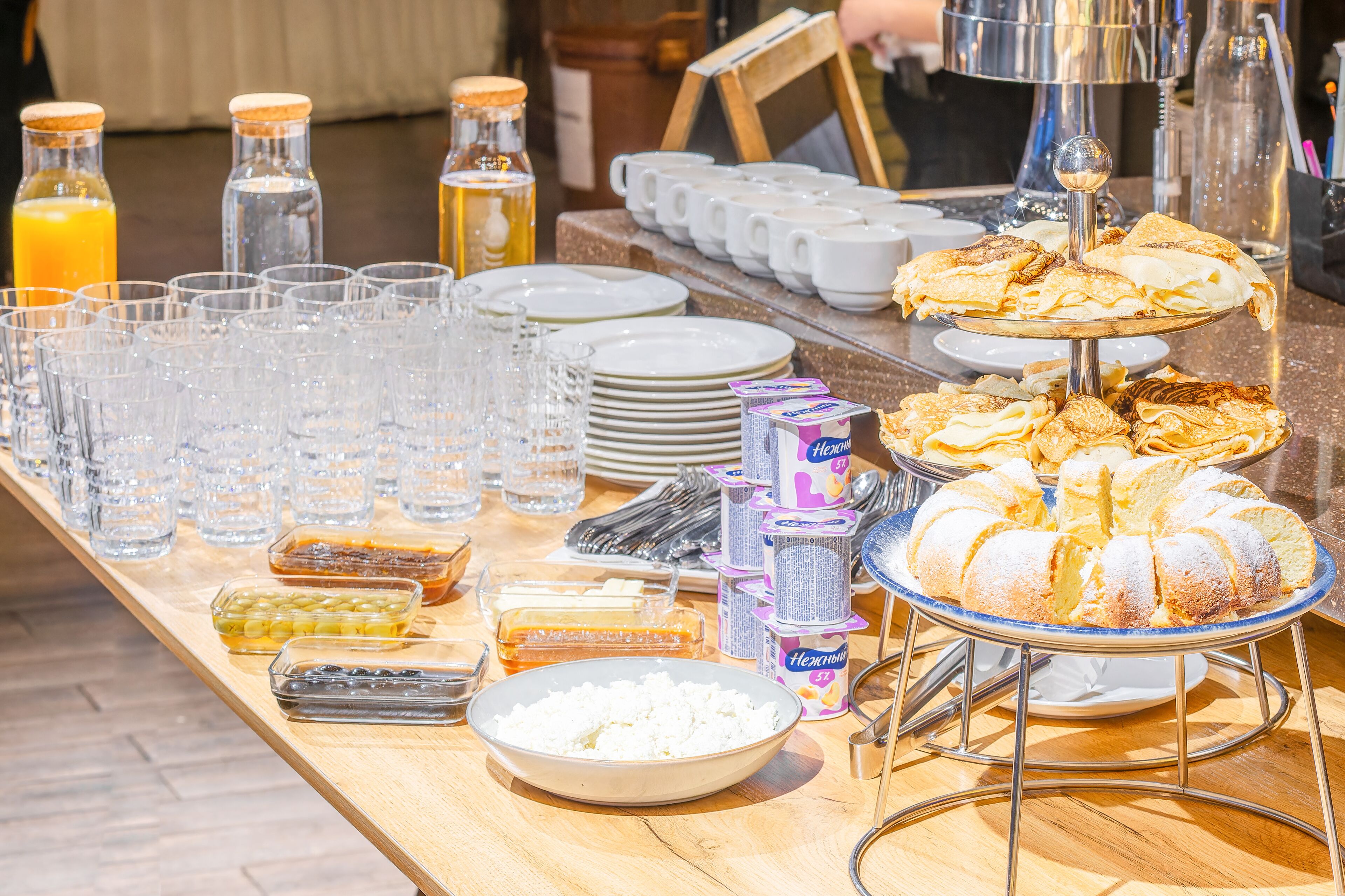 Una mesa de bufé con diversos alimentos, vasos y aderezos.