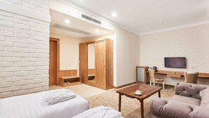 A hotel room with two beds, a sofa, a TV, and a desk with a chair. - Praga Hotel (Tashkent)