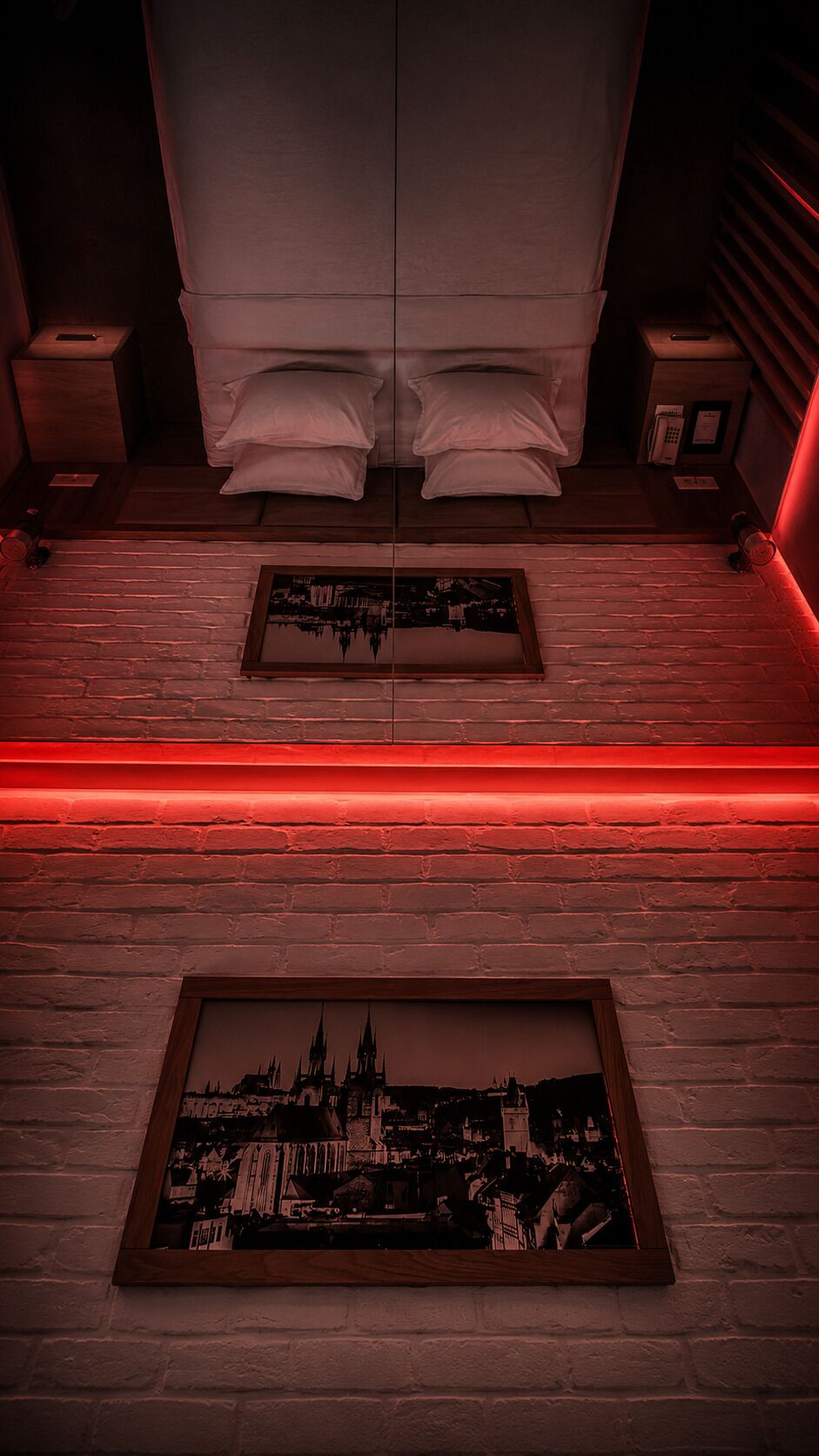 A bedroom with a mirrored ceiling, a red neon light strip, and two framed pictures on the wall.