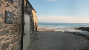 En stenklynge ved stranden, kaldet 'Lime Kiln Cottage', med en grussti, der fører til indgangen.