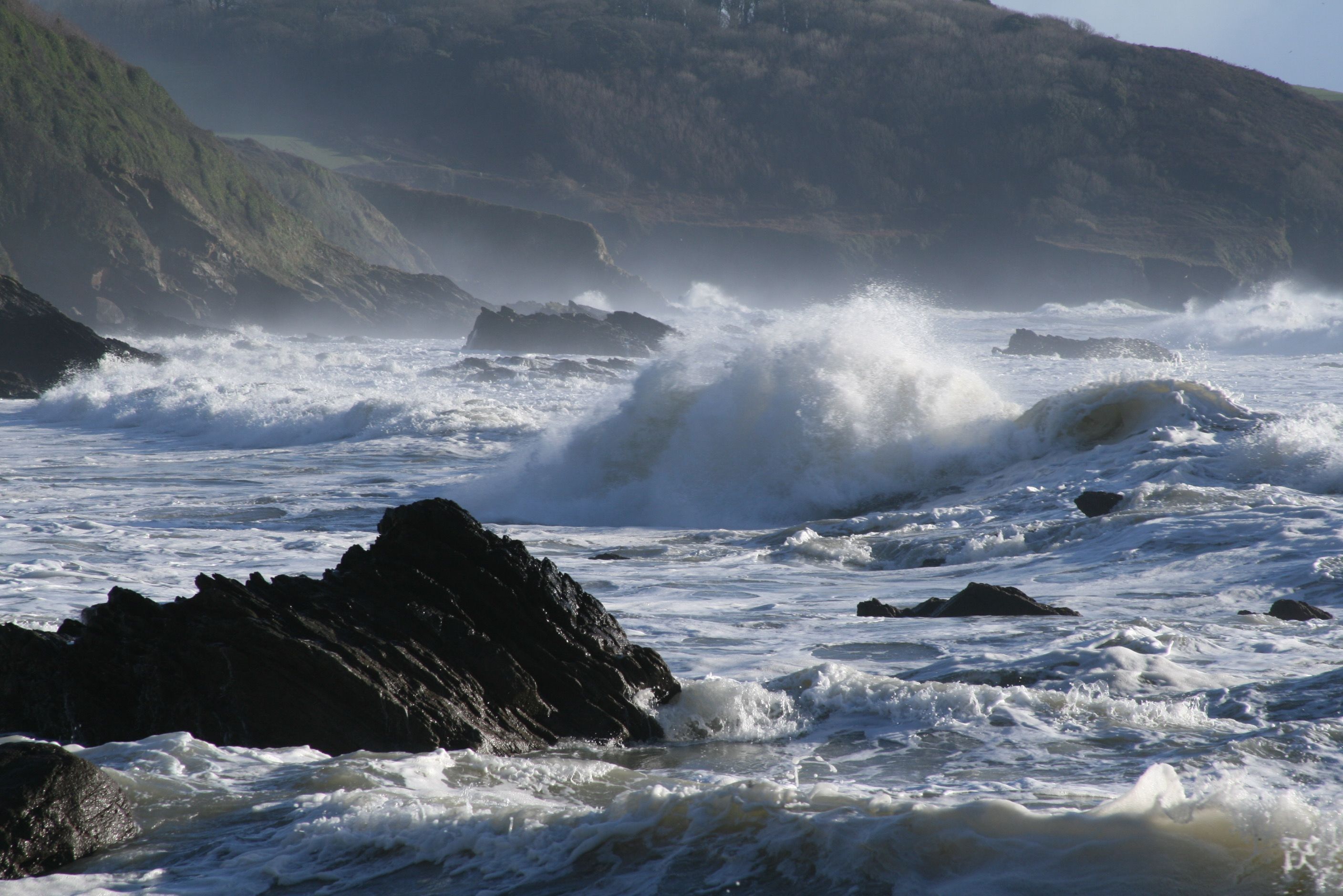 A coastal scene with waves crashing against rocks and cliffs.