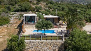 En villa med swimmingpool, stenvægge og udsigt over de omkringliggende bakker.