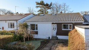 A residential house with a tiled roof, a front door, and a small front yard with a pathway.