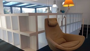 A modern room with a built-in white shelving unit, a brown leather chair, and pendant lighting.