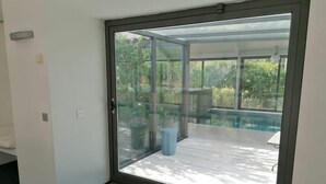 A room with a sliding glass door leading to an outdoor patio with a pool and seating area.
