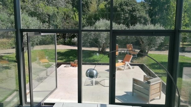 A modern room with large glass windows, a white sofa, and a dining table.