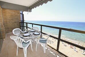 Ein Balkon mit Tisch und Stühlen mit Blick auf einen Strand.