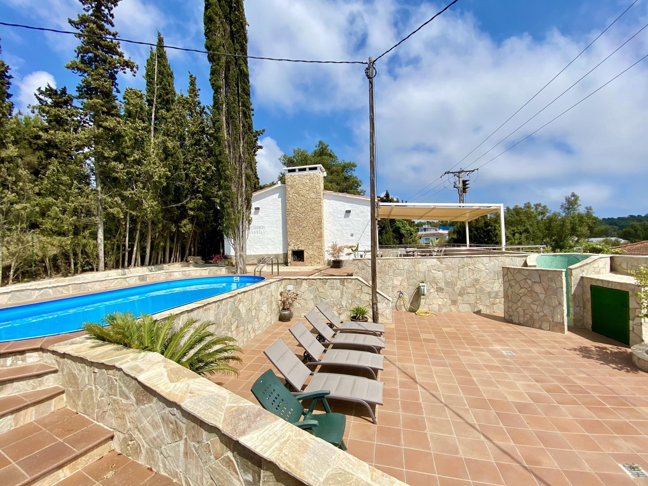 A swimming pool with lounge chairs and a stone wall.