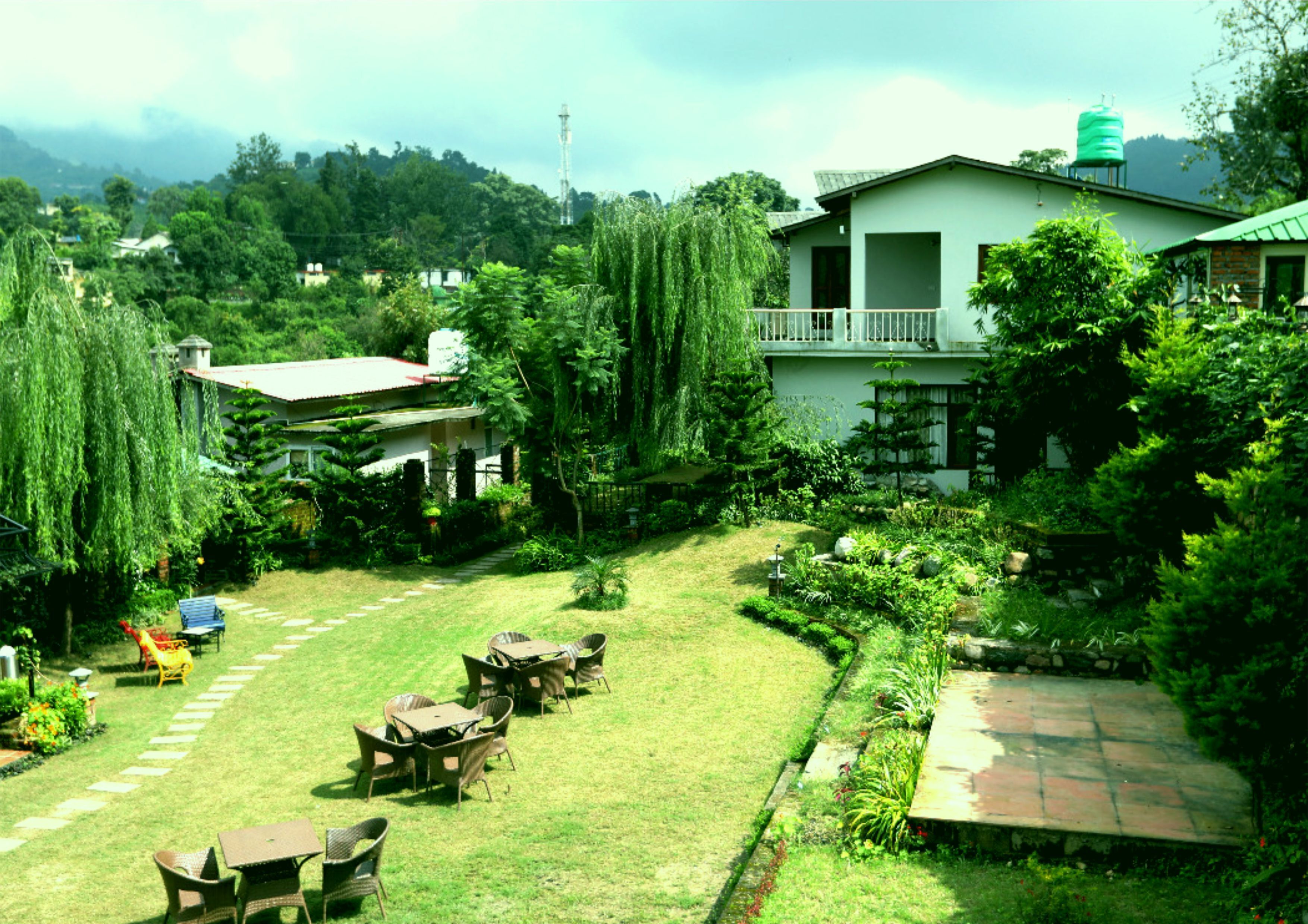 A garden with a lawn, outdoor seating, and a building with a balcony.