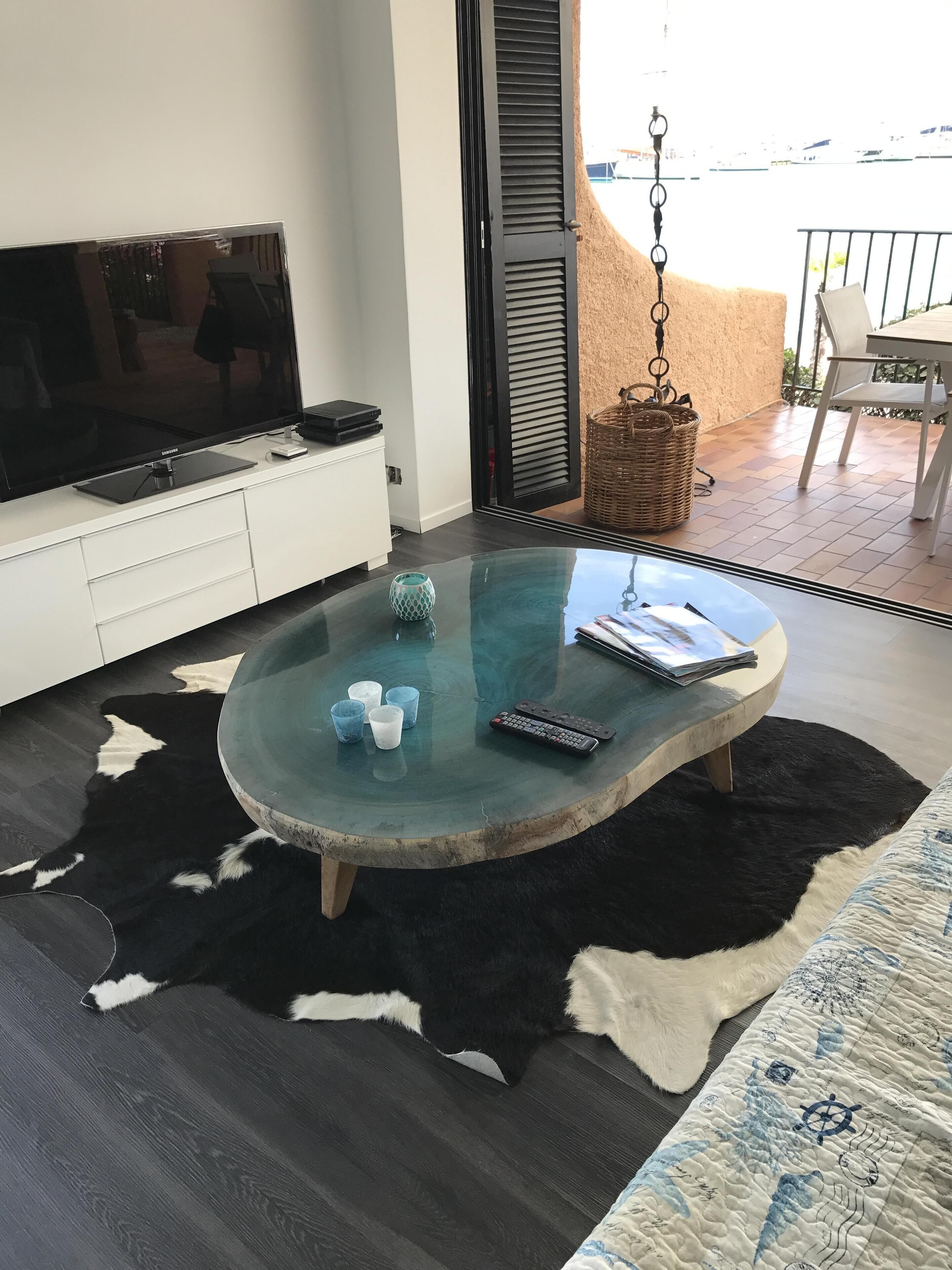 Una sala de estar moderna con una mesa de centro de vidrio, un televisor de pantalla plana y un tapete acogedor.
