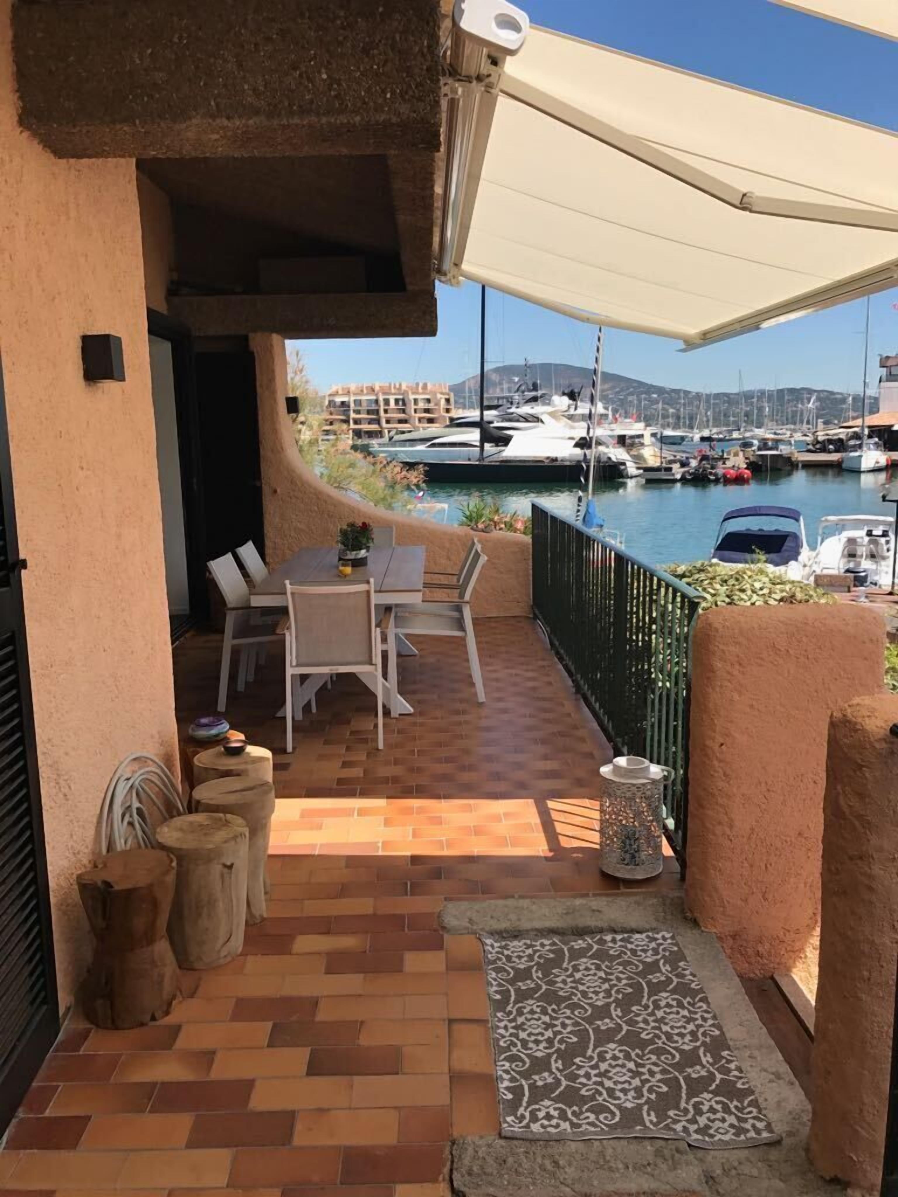 A patio with a table and chairs, a small rug, and a view of a marina with boats.