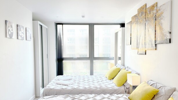 Ein modernes Schlafzimmer mit einem großen Bett, einem Fenster und Kunstwerken an den Wänden.