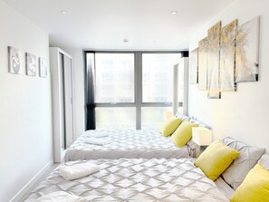 Ein modernes Schlafzimmer mit einem großen Bett, einem Fenster und Kunstwerken an den Wänden.