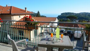 A balcony with a table set for two, overlooking a residential area with houses and a view of the sea. - Nice apartment on the Amalfi Coast and close to the Path of the Gods (Pianillo)