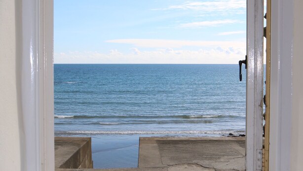 A window with a view of the ocean and a white bowl on the windowsill. - Wonderful reverse level conversion located on the sea front in picturesque rural hamlet on the South (Saint Austell)