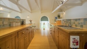 A spacious kitchen with wooden cabinets, a large island, and a view to the dining area. - Wonderful reverse level conversion located on the sea front in picturesque rural hamlet on the South (Saint Austell)