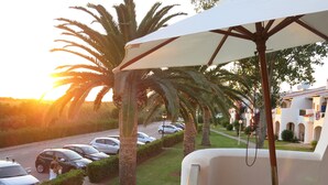 A balcony with a view of parked cars and palm trees, overlooking a street and buildings. - Nice apartment with sea views Son bou (Son Bou Minorca)