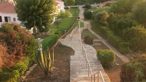A stone staircase leading uphill with metal railings, surrounded by greenery and a clear sky. - Nice apartment with sea views Son bou (Son Bou Minorca)