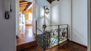 A staircase with a metal railing, a hanging lantern, and a telephone on the wall.