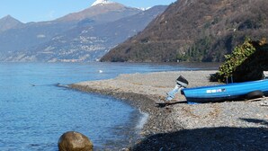 A rocky shoreline with a blue boat and a mountain in the background.