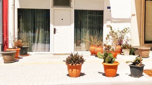 Entrada de un edificio con una puerta blanca, plantas en macetas y un cartel con el número 71.