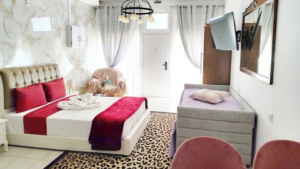 Un dormitorio con cama, sofá, sillón, televisor y espejo.