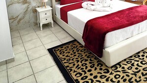 Un dormitorio moderno con pared de diseño de mármol, cabecero capitonado, colcha roja y alfombra de estampado de leopardo.