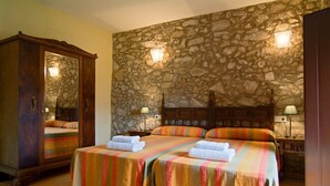 A room with two beds, stone walls, and a wooden wardrobe. - Rural house with pool and jacuzzi (Can Llobet - Canigó) (Capmany)